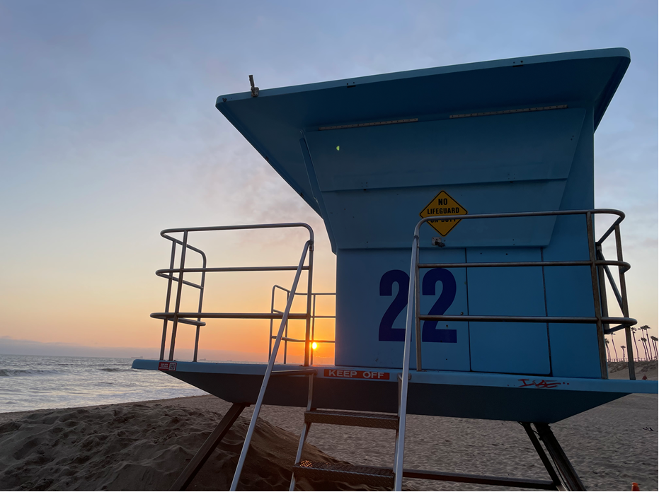A heavy punching bag hanging beneath a wooden pier at golden sunset